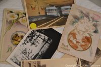 Top side view showing variety of postcard designs including floral, photographic, and bus station scenes.