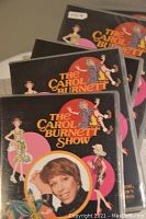 Five DVDs of The Carol Burnett Show stacked showing the cover art with Carol Burnett's photo and colorful cartoon characters representing scenes from the show.
