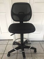 Full side view of the black adjustable fabric office chair showing mesh back and padded fabric seat.