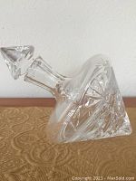Side view of clear crystal decanter lying on its side, showing detailed cut glass geometric patterns.