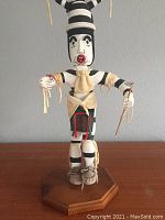 Overall front view of the Hopi Hano Clown Kachina carving showing figure on wooden octagonal base with black and white striped paint and accessories.