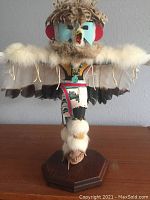 Front view of the Hopi Kachina carving showing detailed feathers, fur, painted face, and apron on wooden base