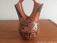 Front view of the reddish-brown water vessel with black geometric and stylized Native American design.