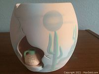 Photo of the pottery vase displaying desert scene design with cactus and sun, including opening housing a small miniature jar inside