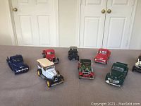 Eight metal model vintage cars arranged on carpet floor, showing variety of models and colors