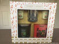 Front view of the boxed Yankee Candle Christmas sampler including two votive candles, one tumbler candle, glass votive holder, and box of tea light candles.