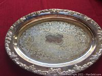 Silver plated oval tray, top side showing engraved detailed floral and scrollwork pattern with grapevine border.