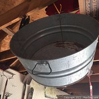 Overhead photo showing inside of large galvanized metal bucket, rust visible on interior base, wire handle detail visible.