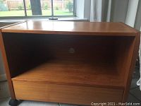 Front view of teak printer table showing open shelf with cable hole and closed drawer.