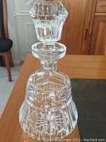 Close-up of crystal decanter upright on table, showing detailed cut glass pattern and faceted stopper.