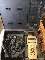 Orange Actron Auto Scanner CP9145 device inside a hard carrying case with multiple diagnostic cables.