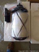 Four Progress Lighting outdoor wall lanterns wrapped in plastic and styrofoam packaging, black metal frame, white diffuser cone, no glass present