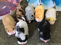 Eight Zhu Zhu Pets robotic hamsters in various colors on carpet