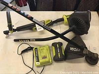Full lot with Ryobi weed wacker, blower, power head, two batteries, and charger displayed on table.