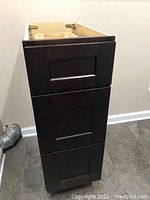 Assembled view of shaker style bathroom vanity base cabinet in espresso with three drawers.