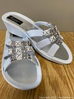 Photo of white Sunblockers sandals showing straps with metallic beads and wedge sole.
