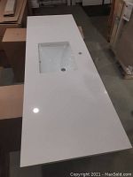 White quartz countertop with integrated rectangular undermount sink and single faucet hole, viewed from above at an angle