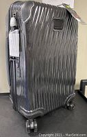 Black Tumi suitcase standing upright showing ribbed exterior, wheels and handle