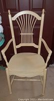 Single image showing a creme antique finished wooden armchair with vertical slat back and padded seat.