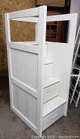 Oblique front view of white wooden bunk bed staircase showing side panels and three visible drawers
