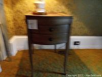 Image of a vintage wooden side table with one drawer and four legs against a yellow textured wall.
