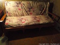 Front view of wooden framed sofa with floral patterned cushions showing wear and need for replacement.