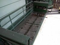 Photo of the green metal frame of a 3-seater glider showing coil spring seating support and metal armrests with some wear and rust.