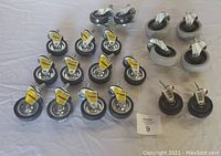 Photo showing 19 caster swivel wheels of sizes ranging 3" to 4", mostly black rubber caster wheels with metal frames, some with labels.