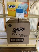 Six box lot showing one open box on top, one boxed shipment below shelf, with MaxSold label