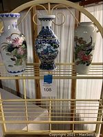 Three Asian inspired decorative vases on a shelf, showing full view of all three.