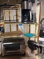 Photo showing Ninja coffee maker, toaster oven, spice rack, and placemats on kitchen shelf.