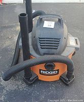 Ridgid Shop Vac vacuum cleaner with hose and wand, showing front and top view of the unit.