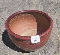 Image showing top view of a large red glazed clay pot with wide opening, visible hairline crack on side and signs of wear.