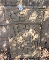 Front view of rectangular brown faux concrete panel with Aztec-inspired carved design.