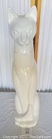 Front view photo of a tall white cat statue with glossy finish and embellished collar