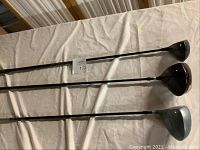 Three golf clubs laid out on a table, showing full shafts and club heads.