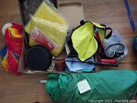 Collection of camping equipment including dome tent fabric, cooking gear, snorkel mask, and accessories in a box.