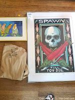 Photo shows the framed Ray Troll 'Spawn Till You Die' art print, the signed Ray Troll t-shirt laid out, and a small framed watercolor of colorful parrots.