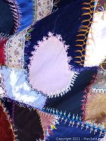 Close-up view showing detailed colorful embroidery stitches on silk and velvet patches, highlighting herringbone stitch variations.