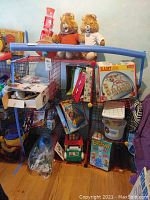 Overview of the assortment of toys and games on red wire shelving including two teddy bears on top and boxed games below