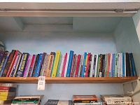 Wide view of a full shelf with about 45 chess books in assorted colors and titles related to chess strategy and instruction.