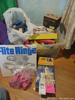 Full lot showing storage bin with assorted blocks, a box of Flipe Rings, and a plastic bag of pink rubber blocks on floor
