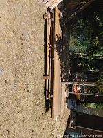 Side view of palletized lumber showing various widths stacked outdoors on grass with sunshine and shadows from nearby trees.