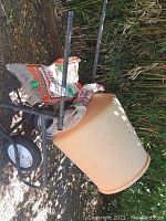 Side angle view showing orange drum mounted on black frame with two wheels and handles