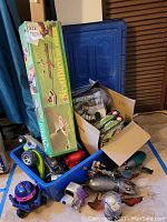 Overview of the box and container with various remote control toys and parts including a green remote control car, and a long green box for a toy aircraft set.