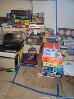 Photo showing stacked board games including Hannibal, Waterworks, Khet, AC/DC, Lost Treasure, Careers, Catan, Lord of The Rings, Trilogy, Dice games and others in varying condition with visible wear