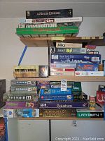 Shelf with stacked board game boxes and puzzles; various titles visible