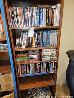 Full view of wooden shelving unit with DVDs, VHS, CD-ROMs, and books arranged on four shelves