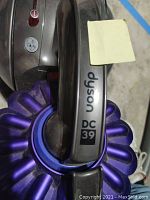 Close-up photo of the Dyson DC39 label on the vacuum handle showing the purple cyclone chamber.