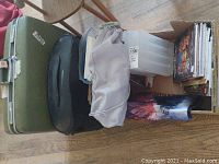 Overview of all items including three luggage pieces and box containing Dungeons and Dragons books and accessory organizer.